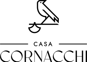 A minimalist black logo design featuring a bird perched on a scale above the text CASA CORNACCHI.