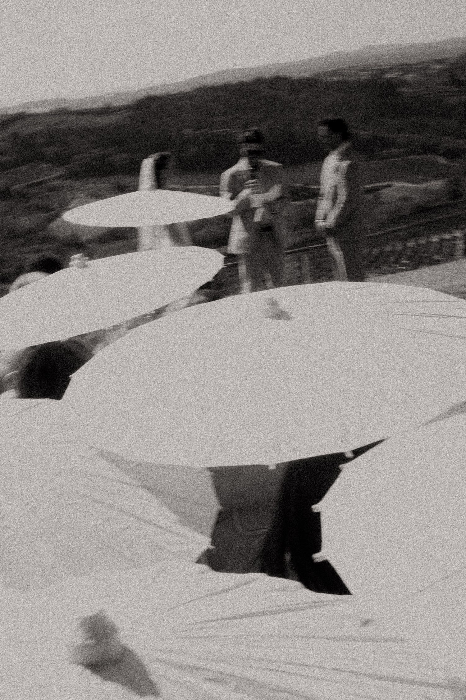 Black and white photo of people gathered on a rooftop terrace surrounded by large white umbrellas outdoors.