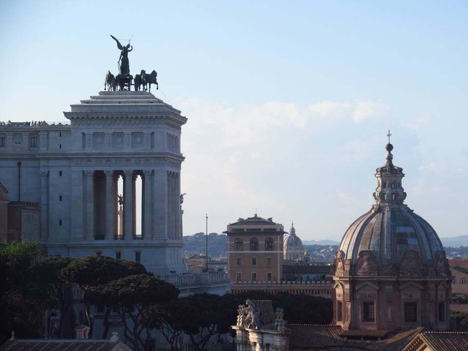 Historic Roman architecture and domes against a blue sky in the city center.