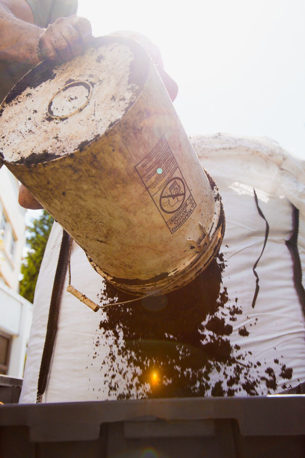 Soil or dirt being dumped from a large industrial bucket in an outdoor construction setting.
