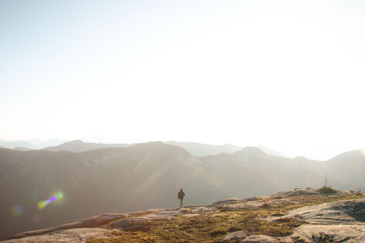 Lone hiker silhouetted on mountain ridge during sunrise.