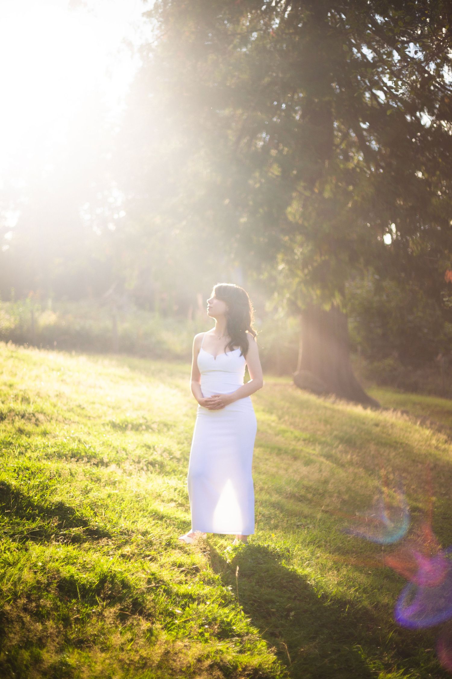 White-dressed figure standing in golden sunlit field during magic hour.