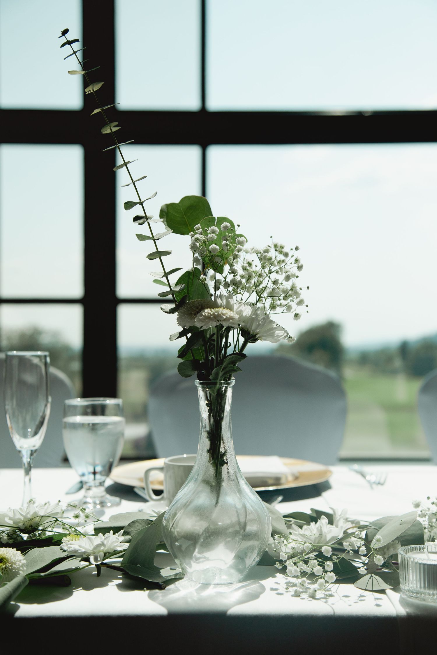 Minimalist floral arrangement with baby's breath in glass vase against window with natural light.