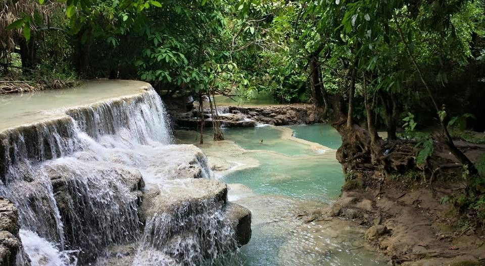 Tropical waterfall cascading into turquoise pools surrounded by lush vegetation.