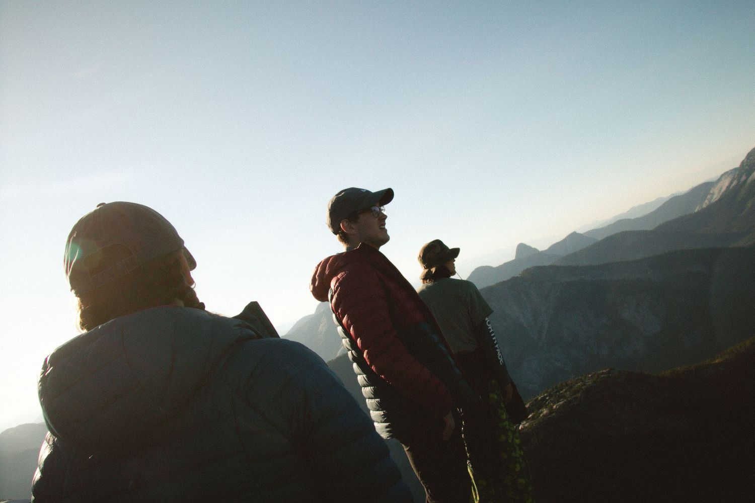 A silhouetted group of hikers enjoying a scenic mountain vista at sunset.