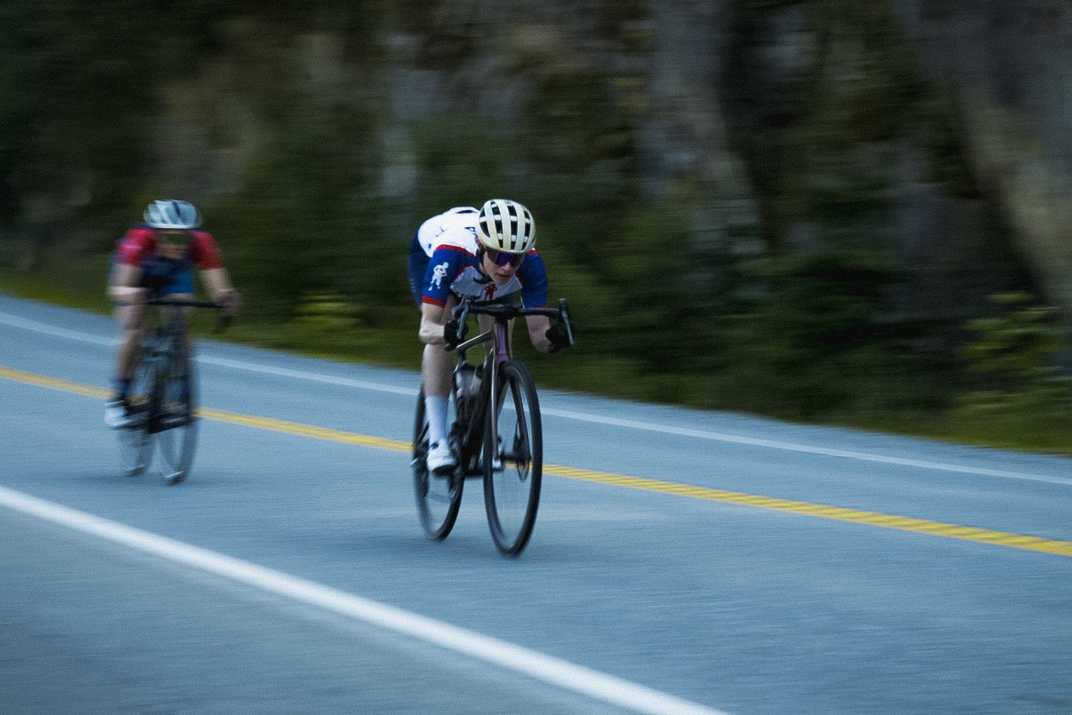 Motion-blurred cyclists racing at high speed on a mountain road.