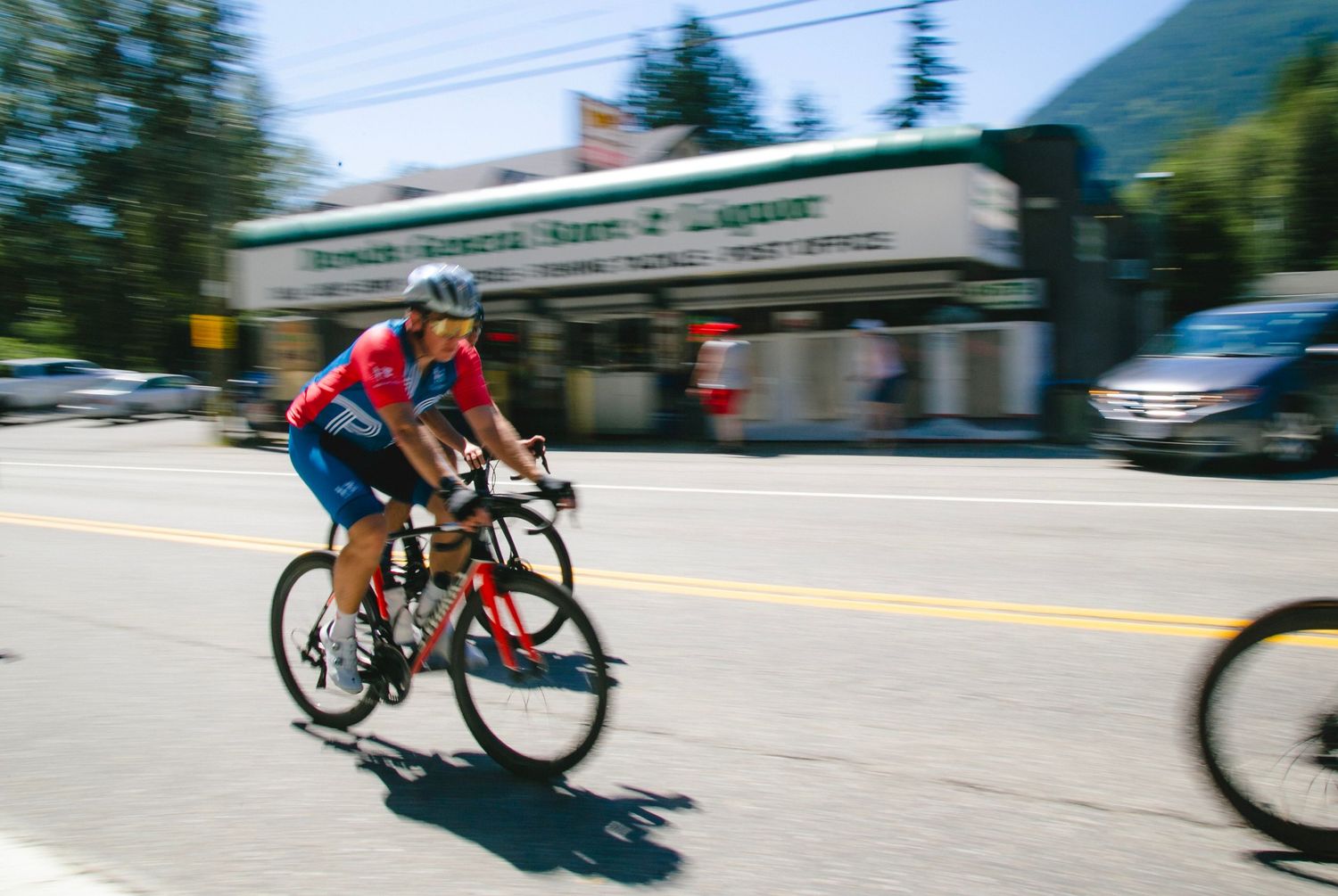 Motion-blurred cyclist pedals through town street on racing bicycle.