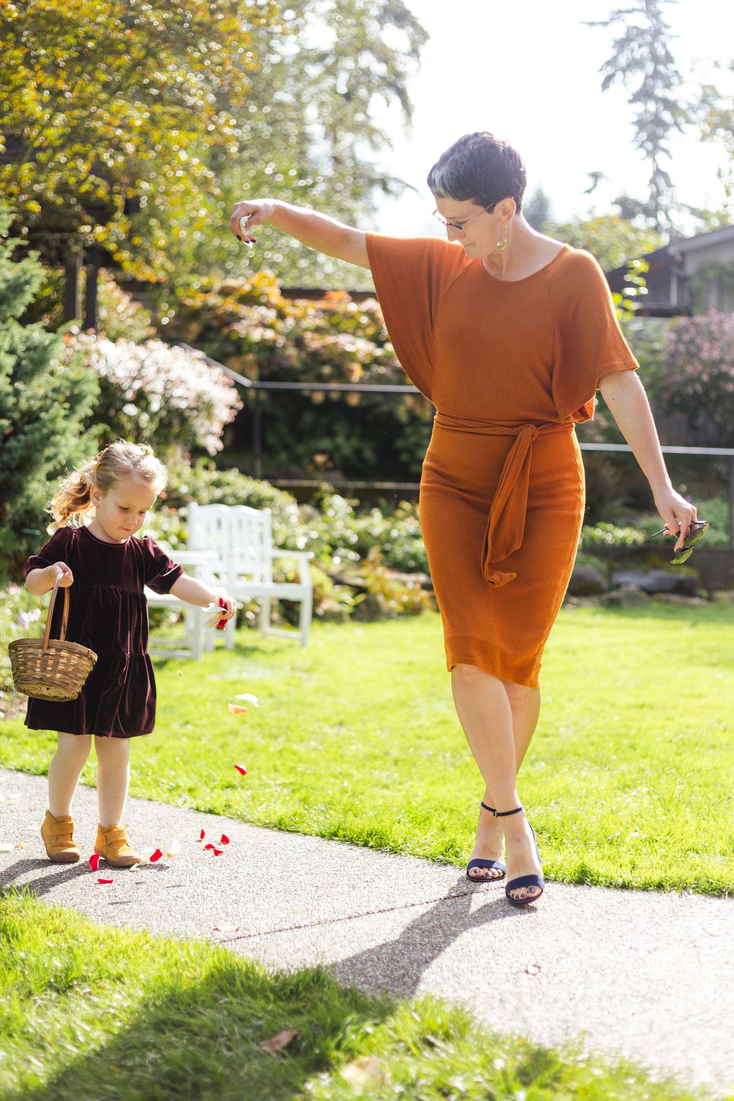 Mother and daughter walking together in a garden on a sunny afternoon.