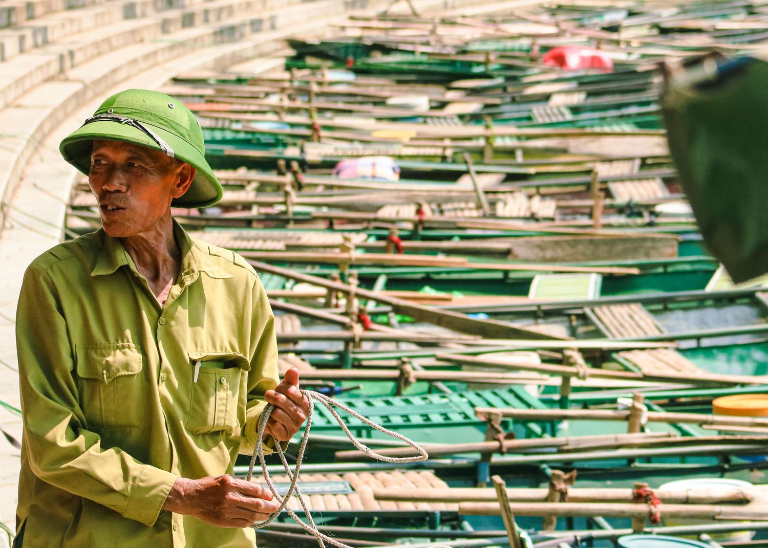 Dock worker in green hat managing rows of stacked fishing equipment.