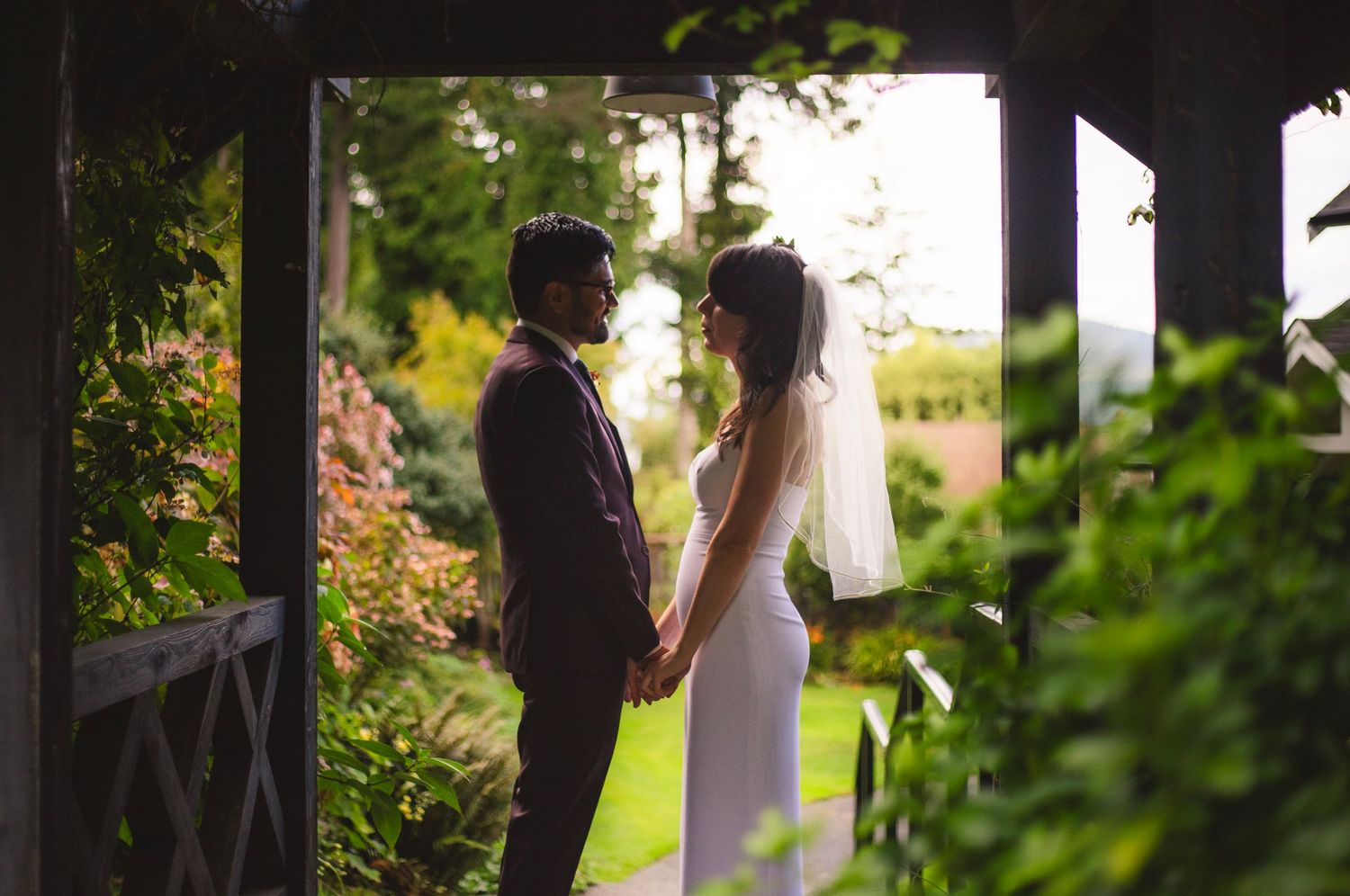 Silhouetted couple shares an intimate moment under a garden arbor during their wedding.