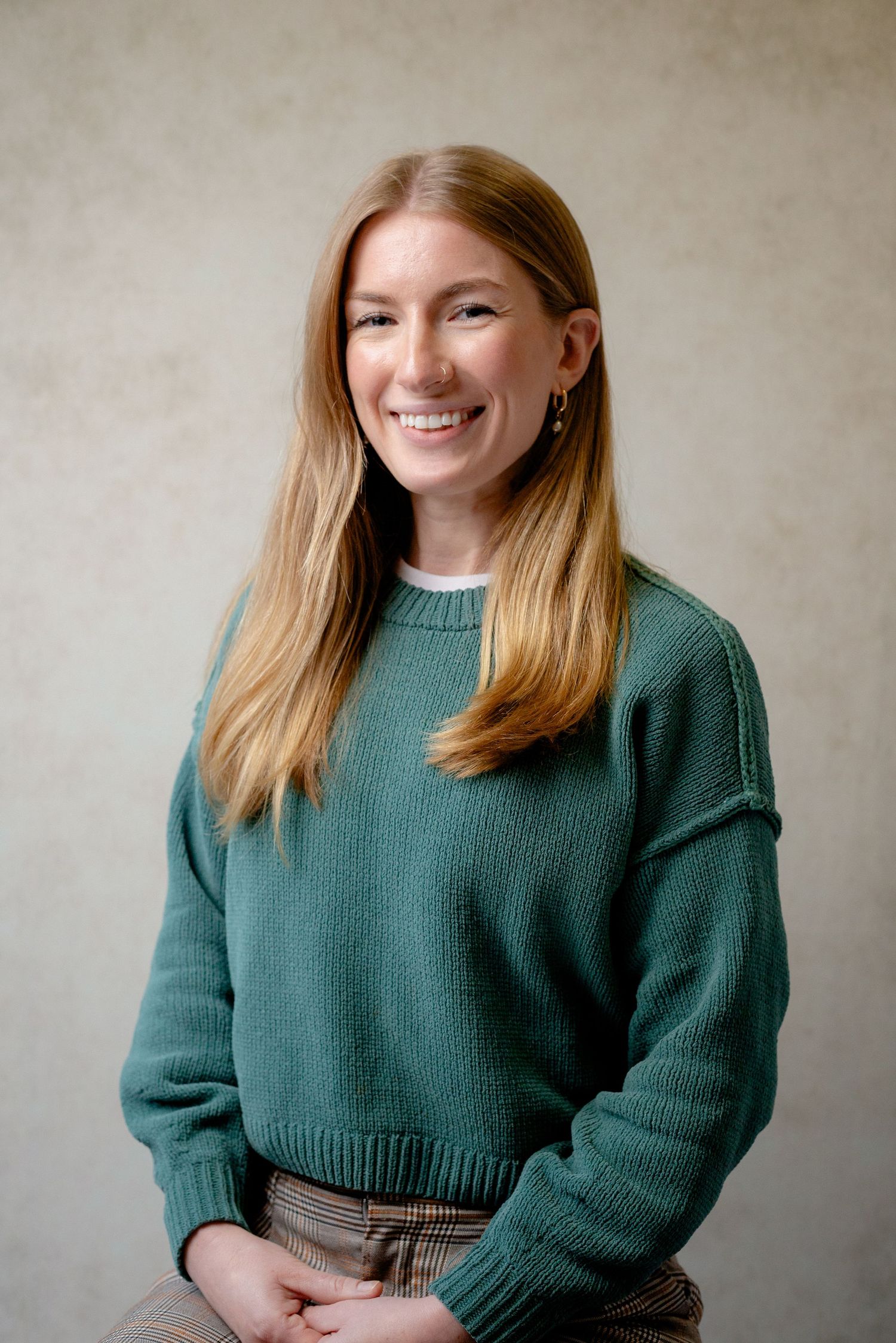 Professional portrait of someone wearing a cozy green sweater against a neutral background.