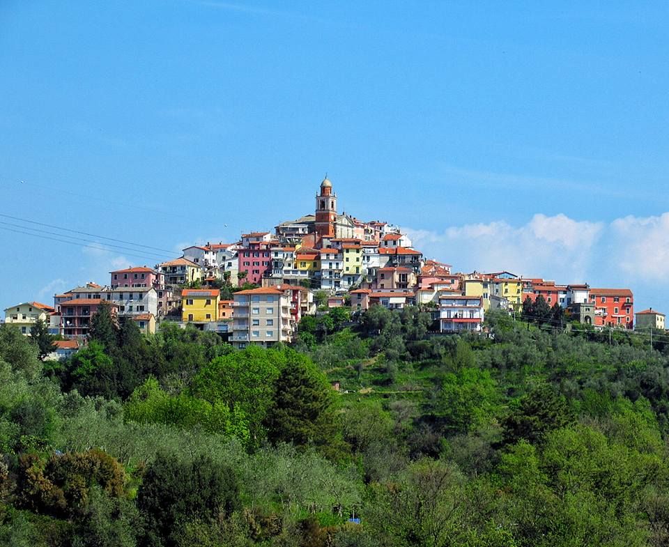 Colorful hillside Mediterranean village with clustered buildings rising up the slope.