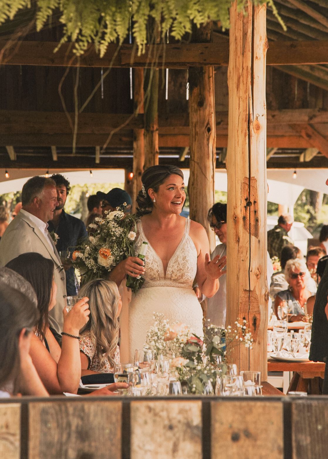Reception celebration in a rustic wooden barn decorated with flowers and string lights.