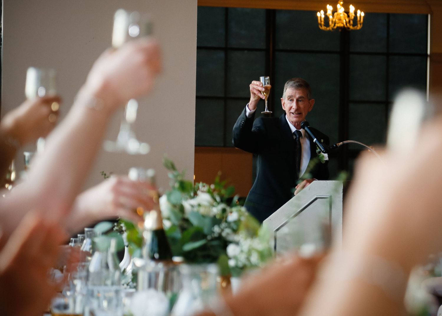 A guest raises a toast during an elegant wedding reception with decorative table settings.