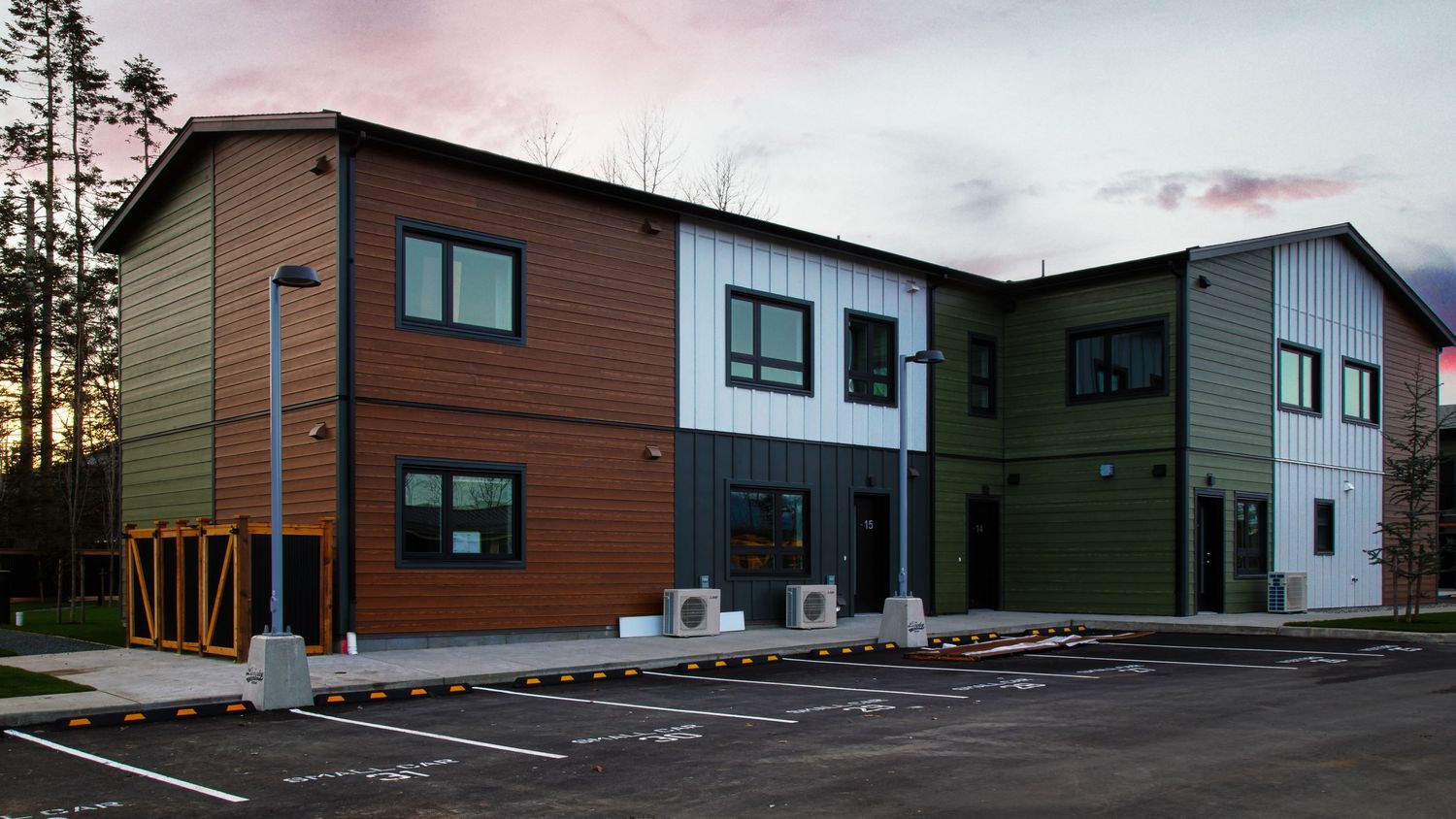 Modern multi-colored townhouse complex with varied architectural elements at sunset.