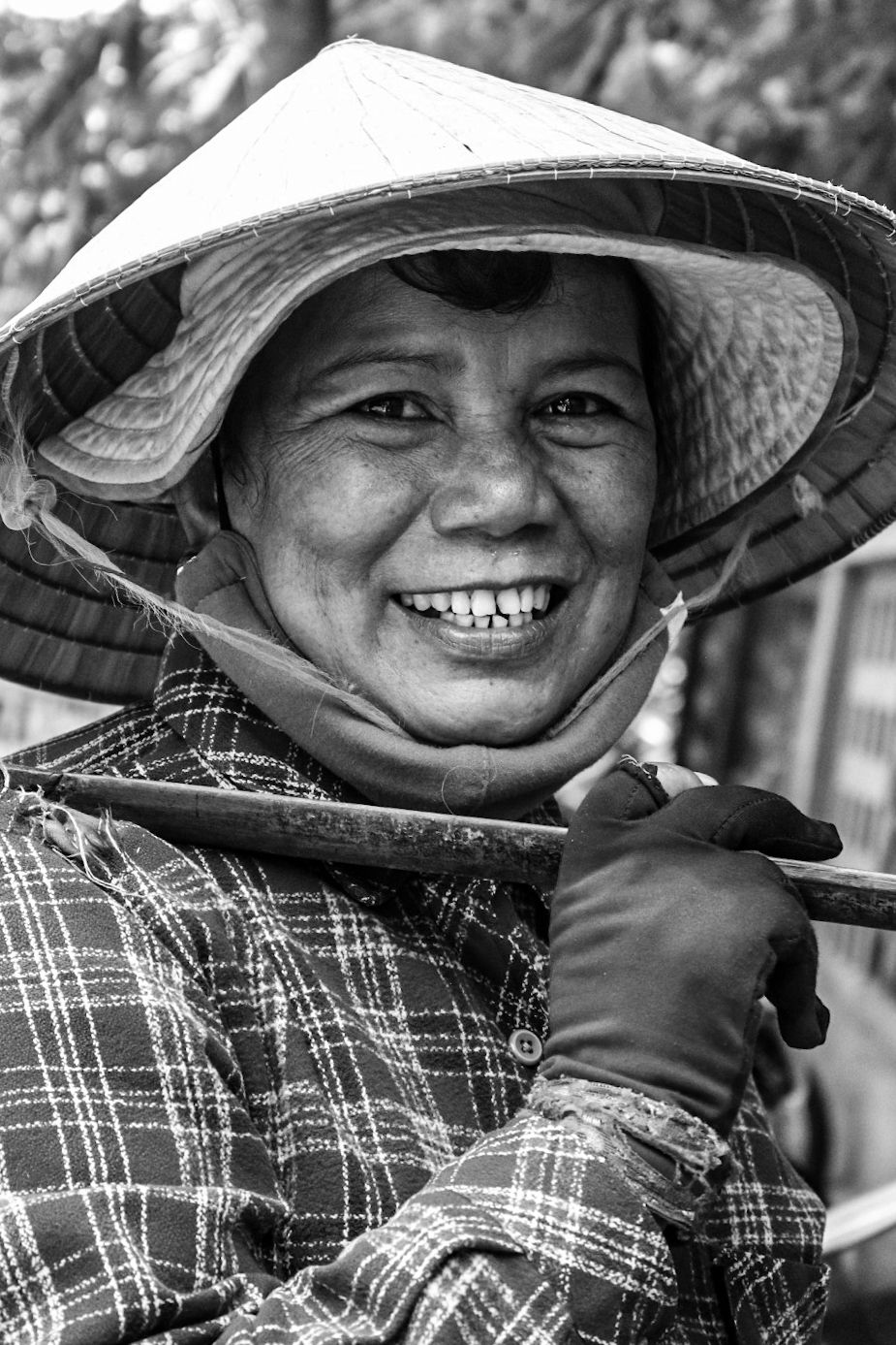 A traditional conical hat and plaid clothing in black and white photography.