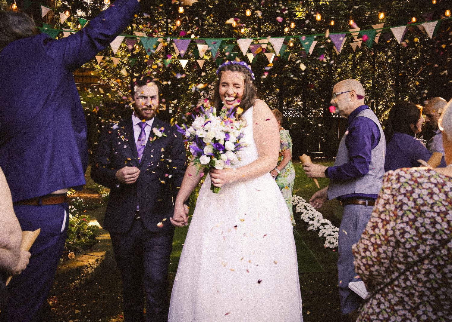 Wedding celebration with colorful bunting and confetti in an outdoor garden setting.