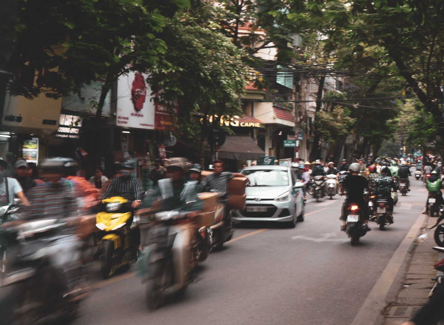 Busy street scene with motion-blurred motorcycles and scooters in Asia.