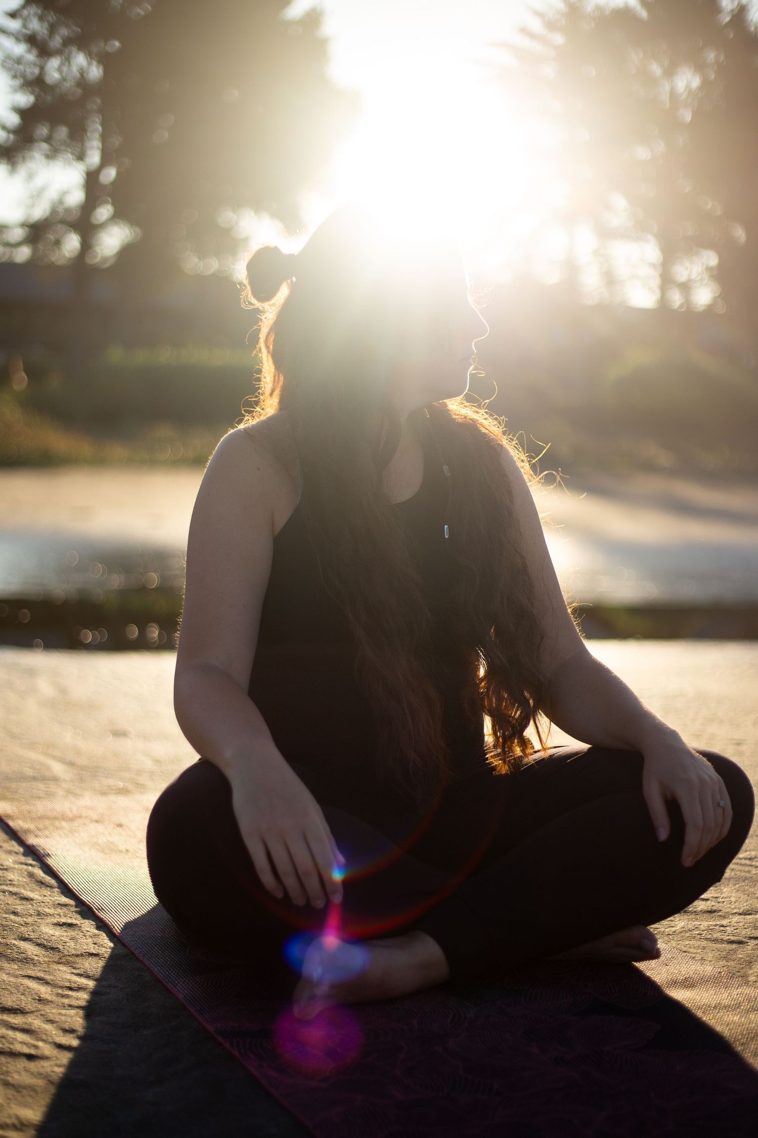 Silhouette of person meditating on a mat during golden hour sunset.