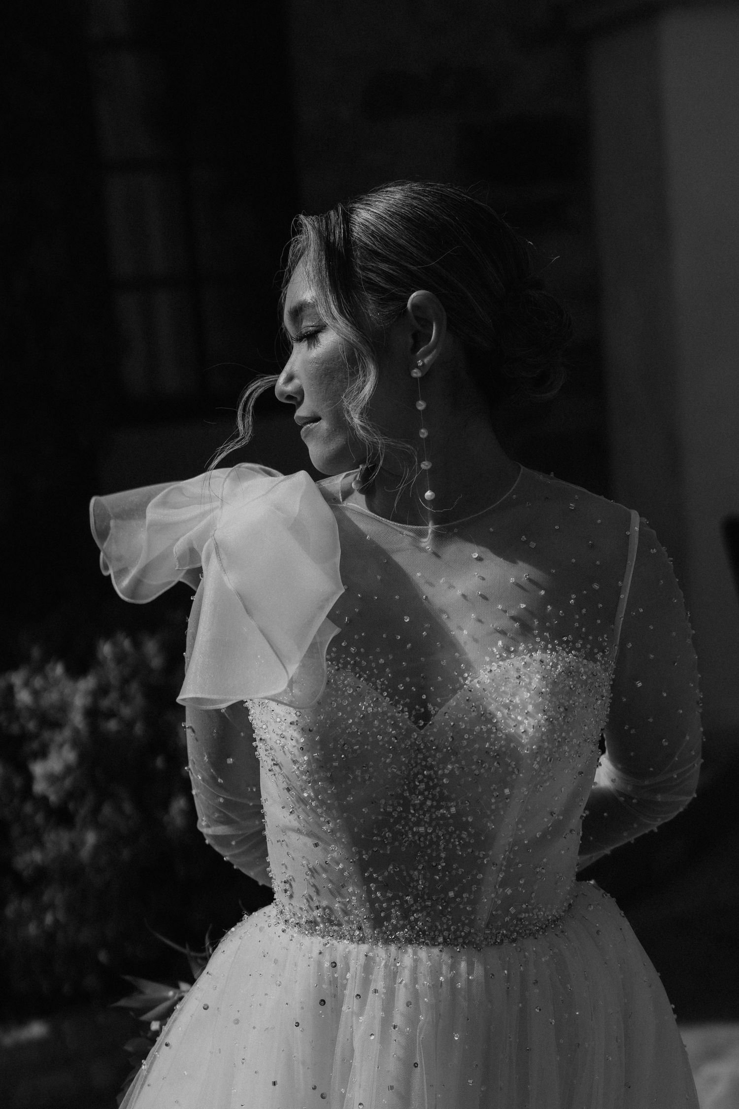 A dramatic black and white portrait of a bride in a sparkly gown with ruffled details.