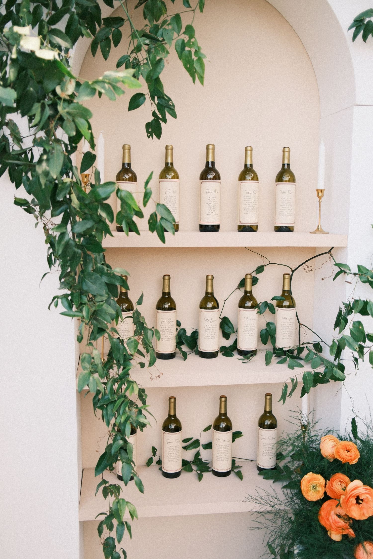 Wine bottle display with green vines in arched alcove shelving.