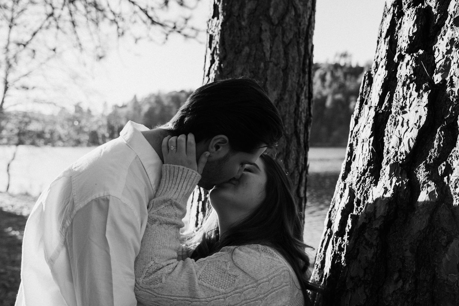 Black and white photo of tender moment between couple by tree.