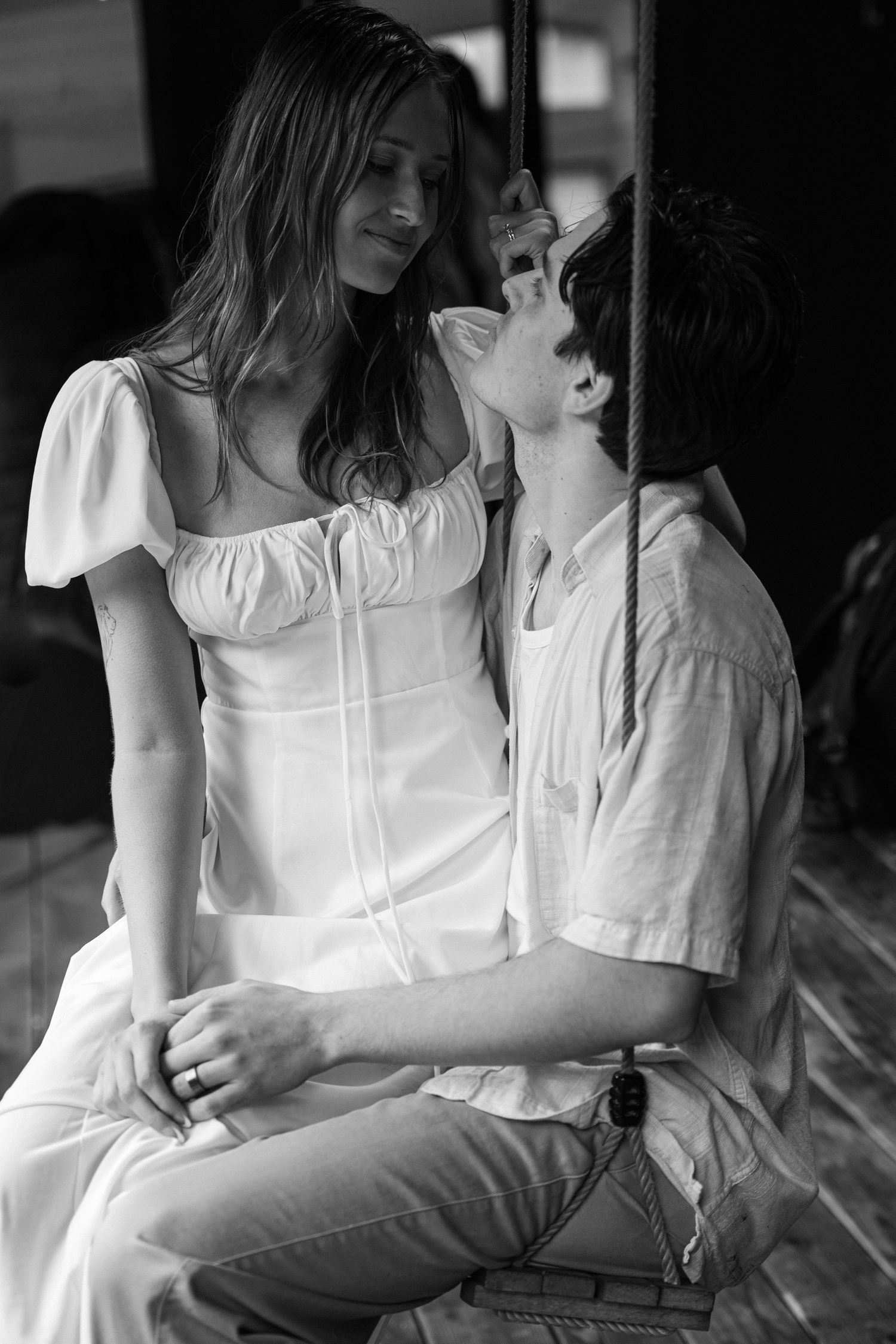 Romantic black and white portrait of couple in white clothing sitting together in intimate pose.