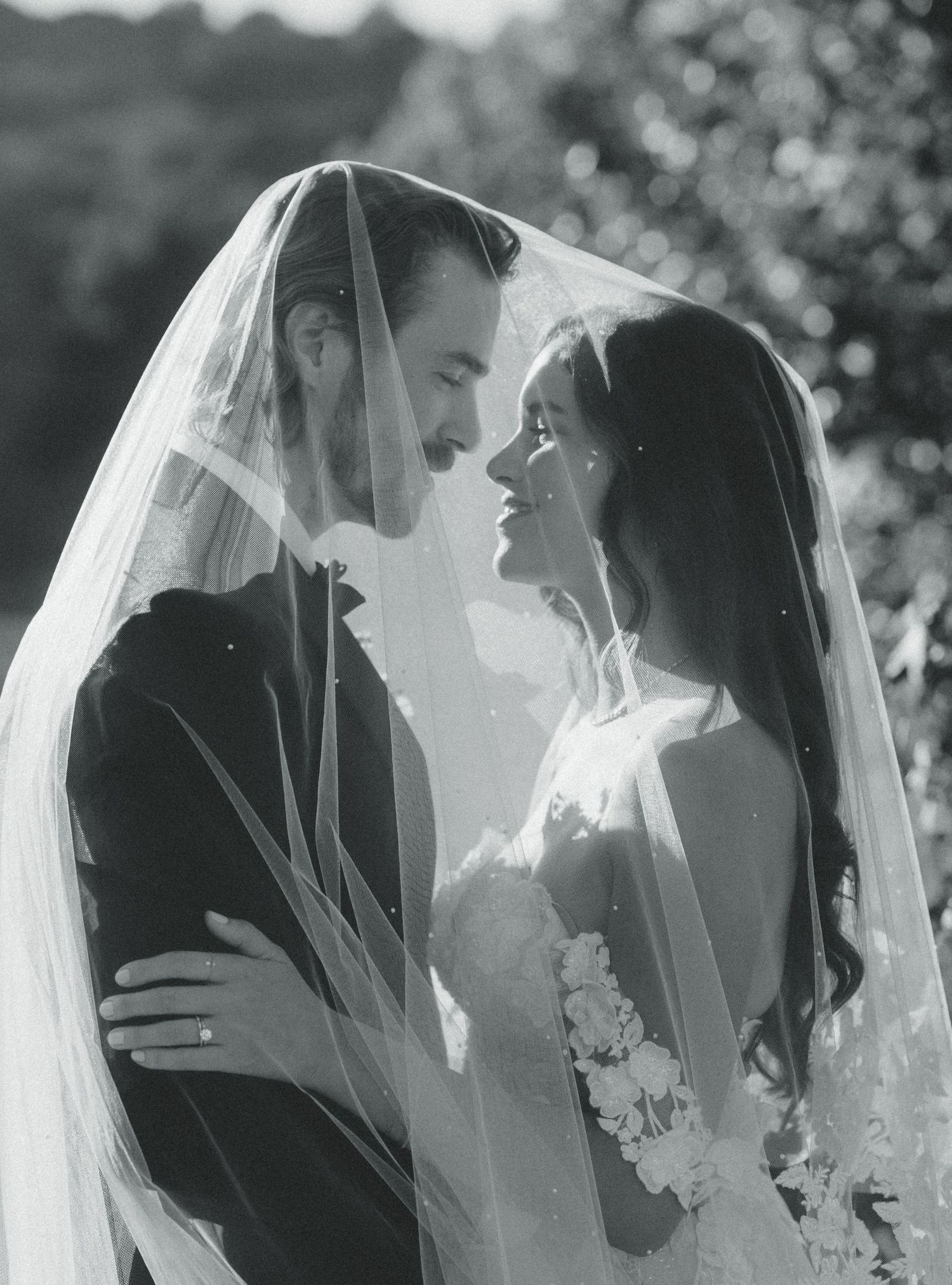 Black and white portrait of a tender moment shared under a wedding veil.