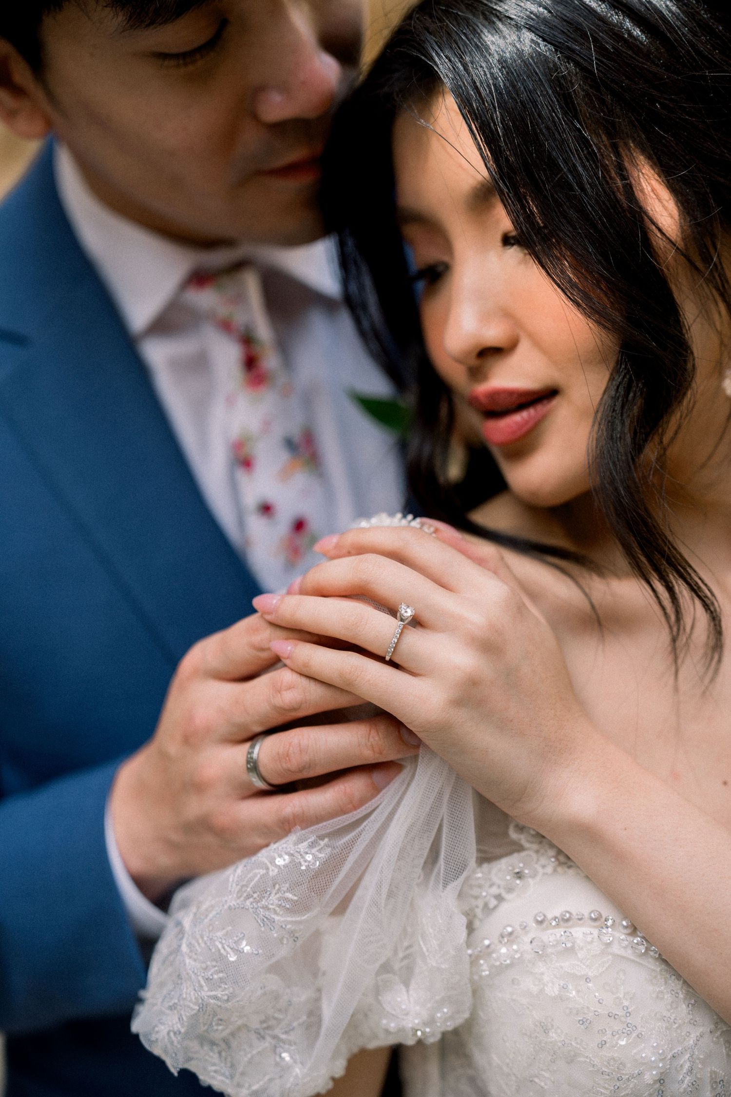 Close-up of newlyweds sharing intimate moment while showing wedding rings.