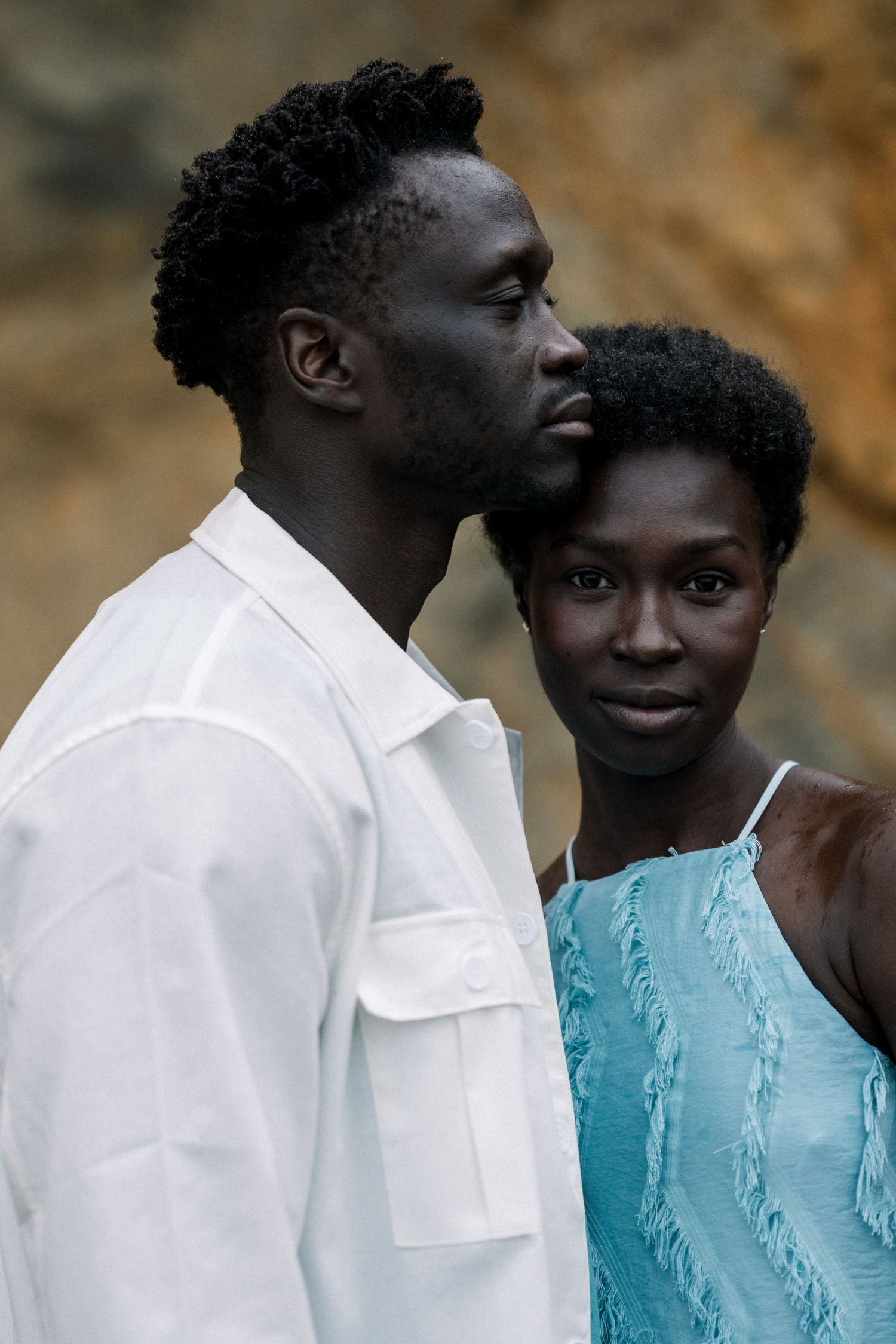 Intimate couple's portrait showcasing connection against warm-toned cave background.