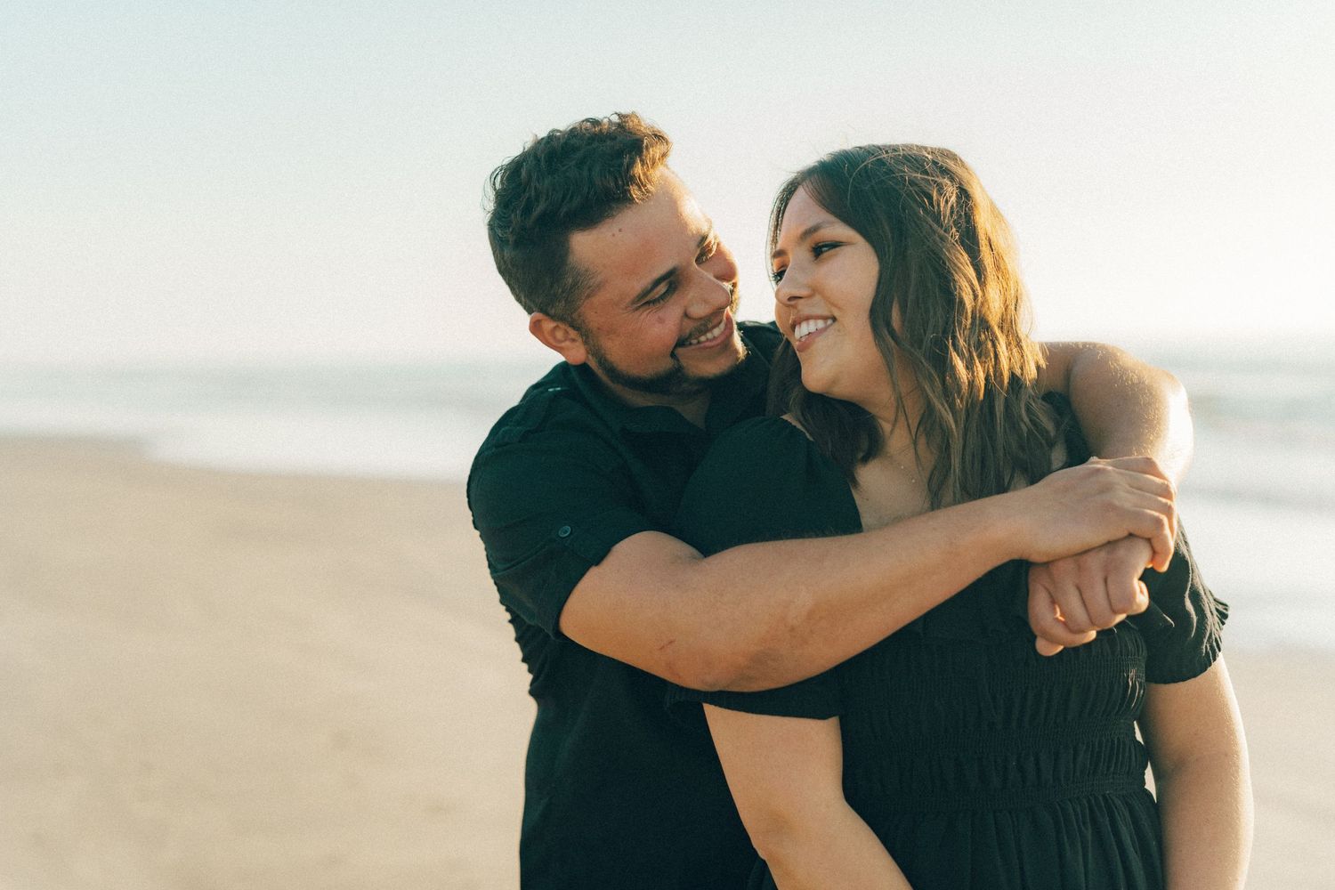 Joyful couple sharing loving moment on sunny beach.