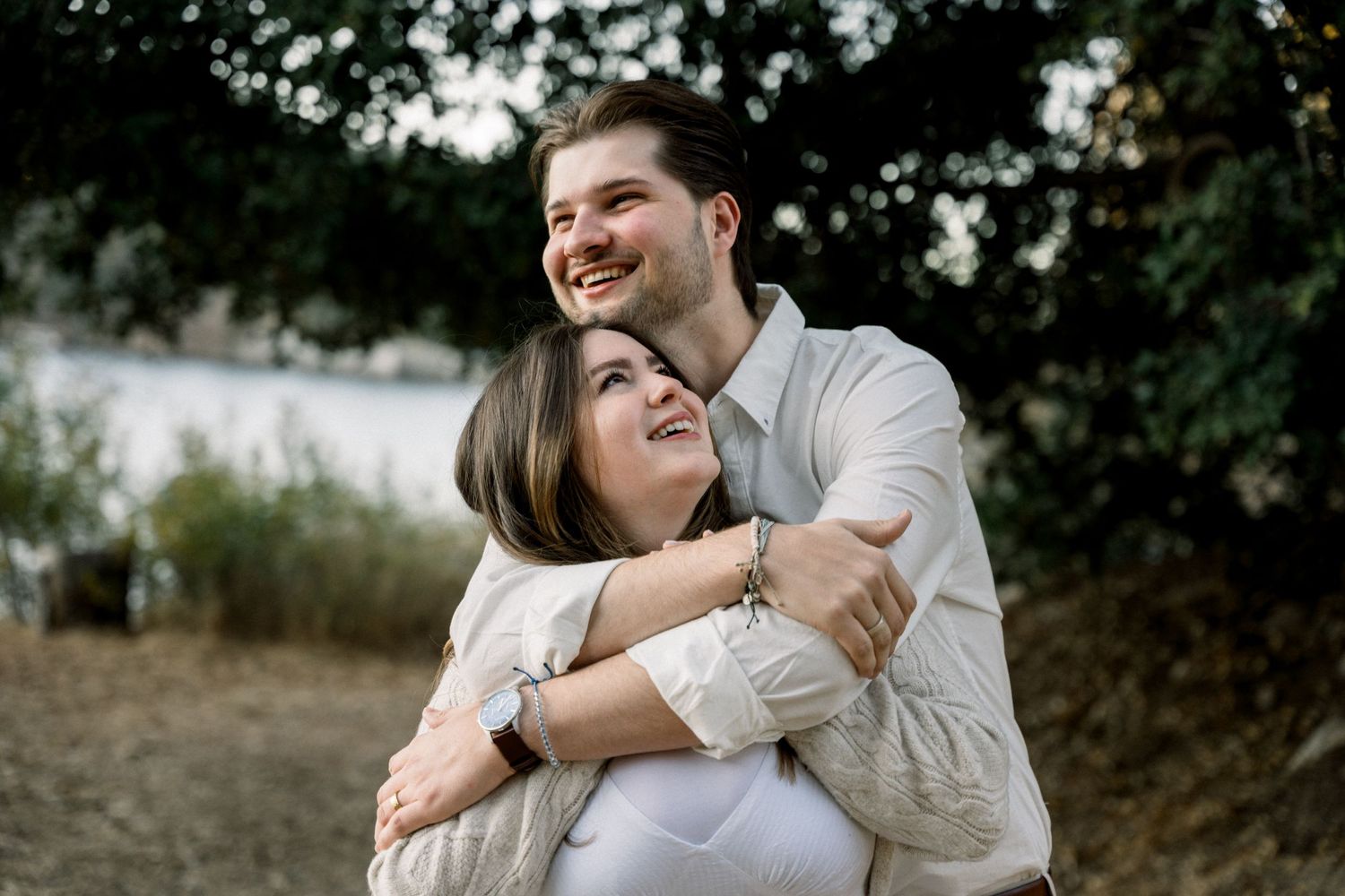 Joyful couple embraces outdoors while sharing a candid laughing moment together.