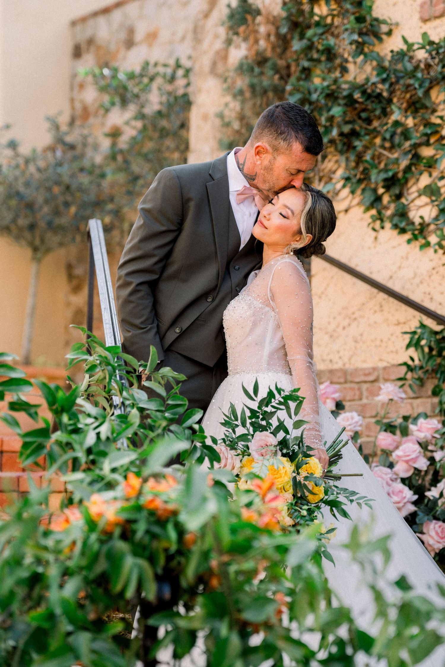 An intimate wedding moment captured in a garden setting with lush greenery and flowers.