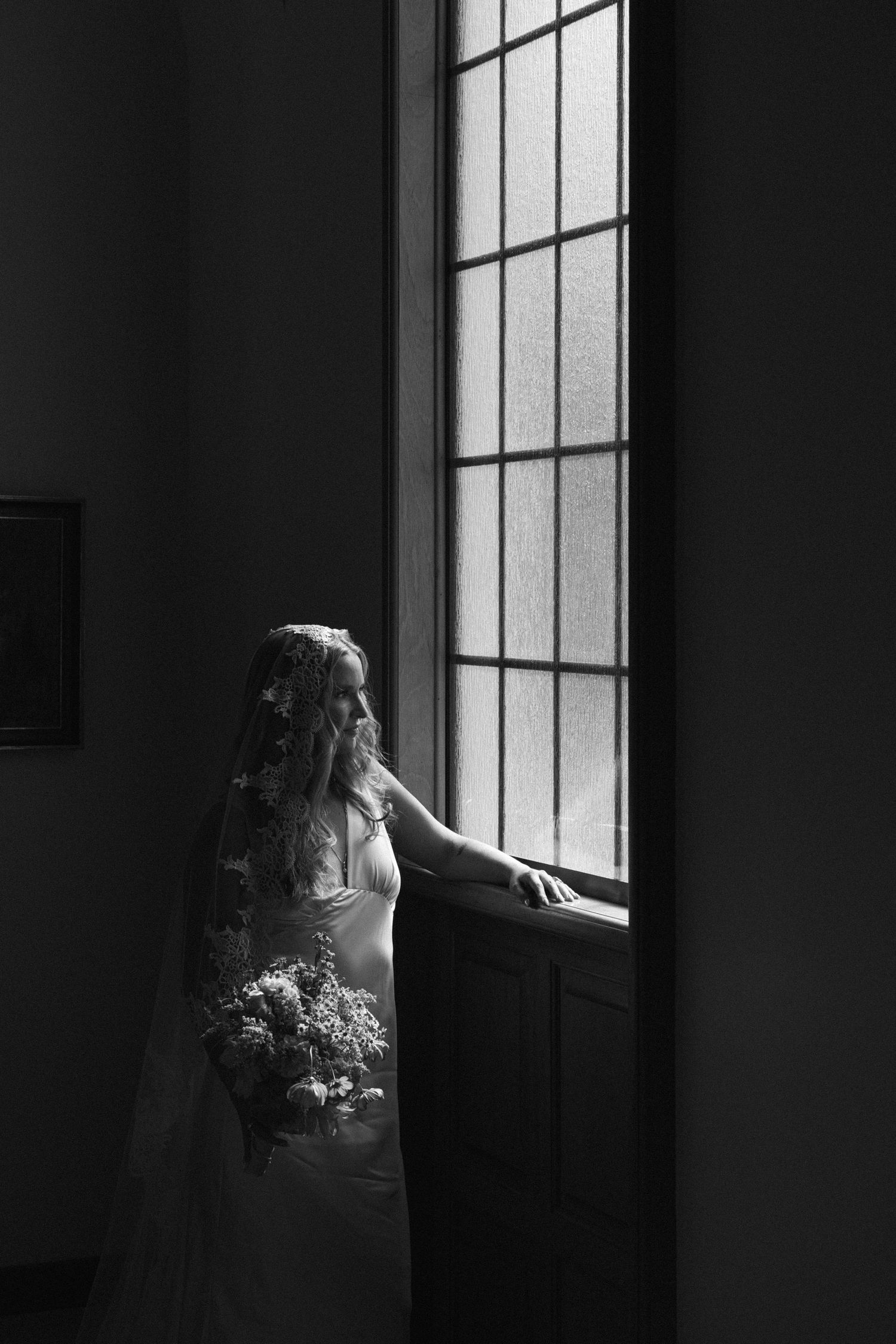 Black and white image series showing figure sitting by large windows in dramatic contrast lighting with shadows.