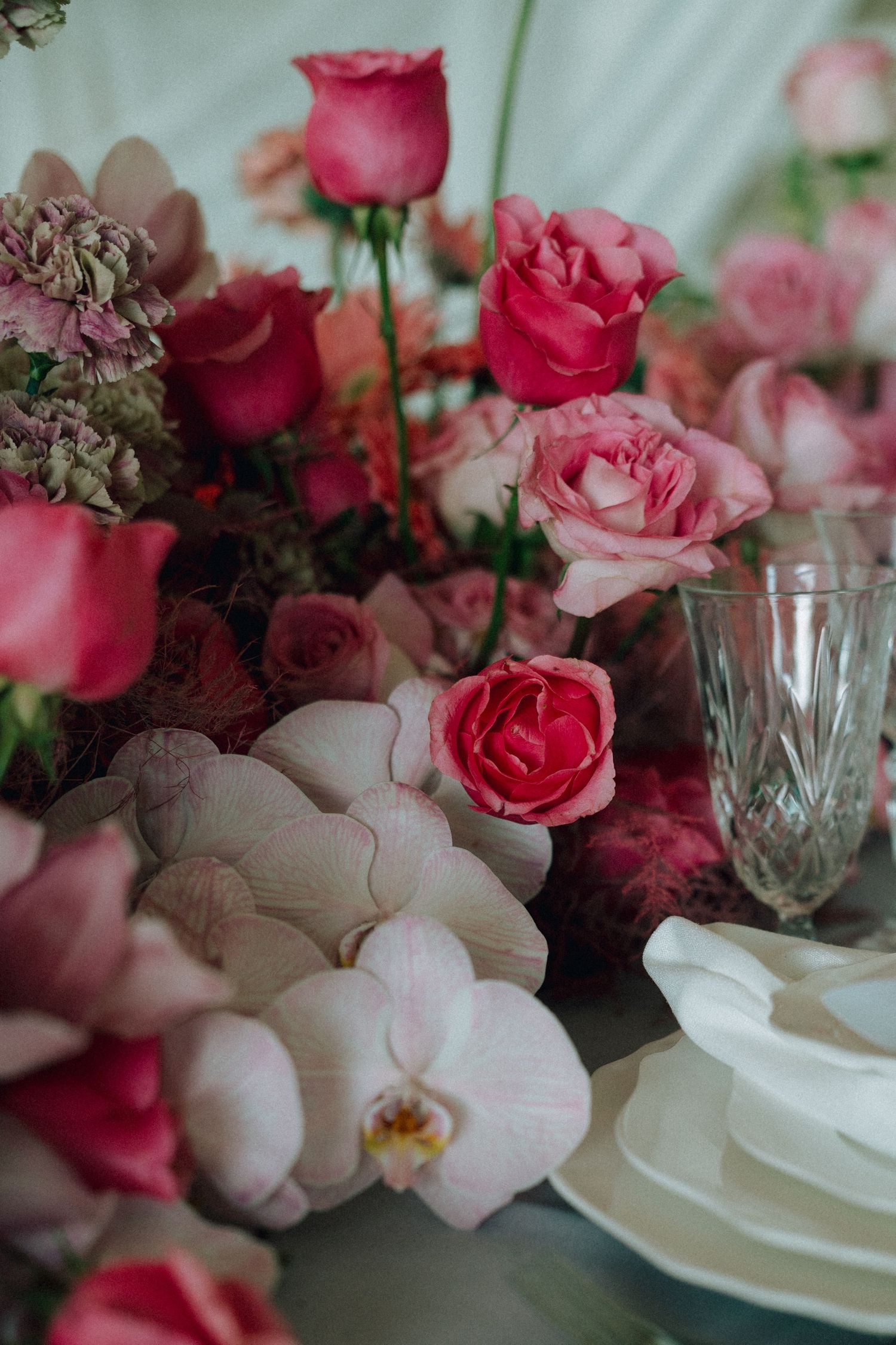 Luxurious floral centerpiece with pink roses, orchids and vintage crystal glassware.
