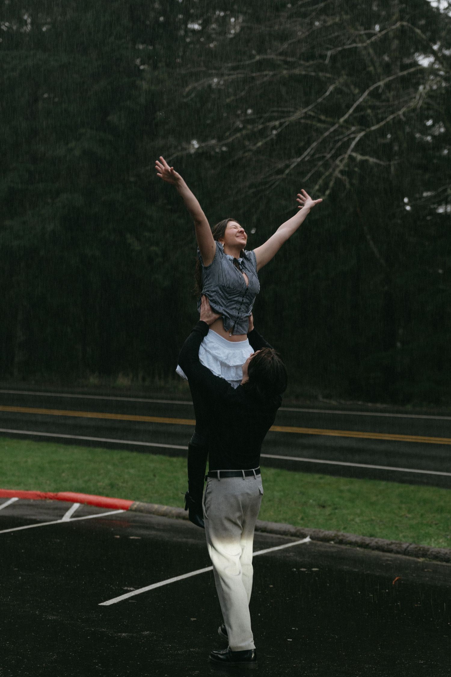 Couple recreates classic lift pose in empty parking lot on rainy day.
