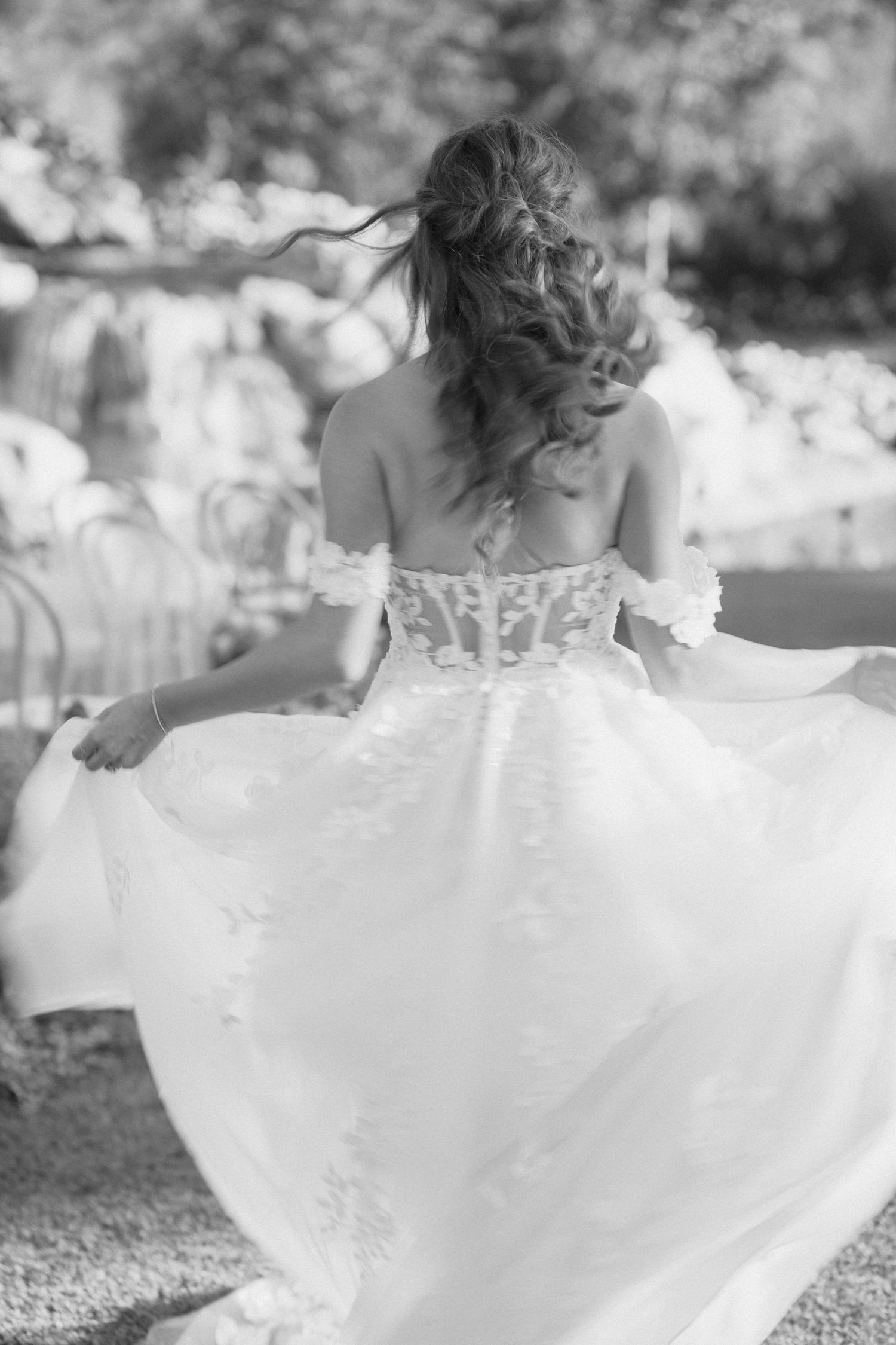 Black and white photo of bride twirling in flowing wedding dress outdoors.