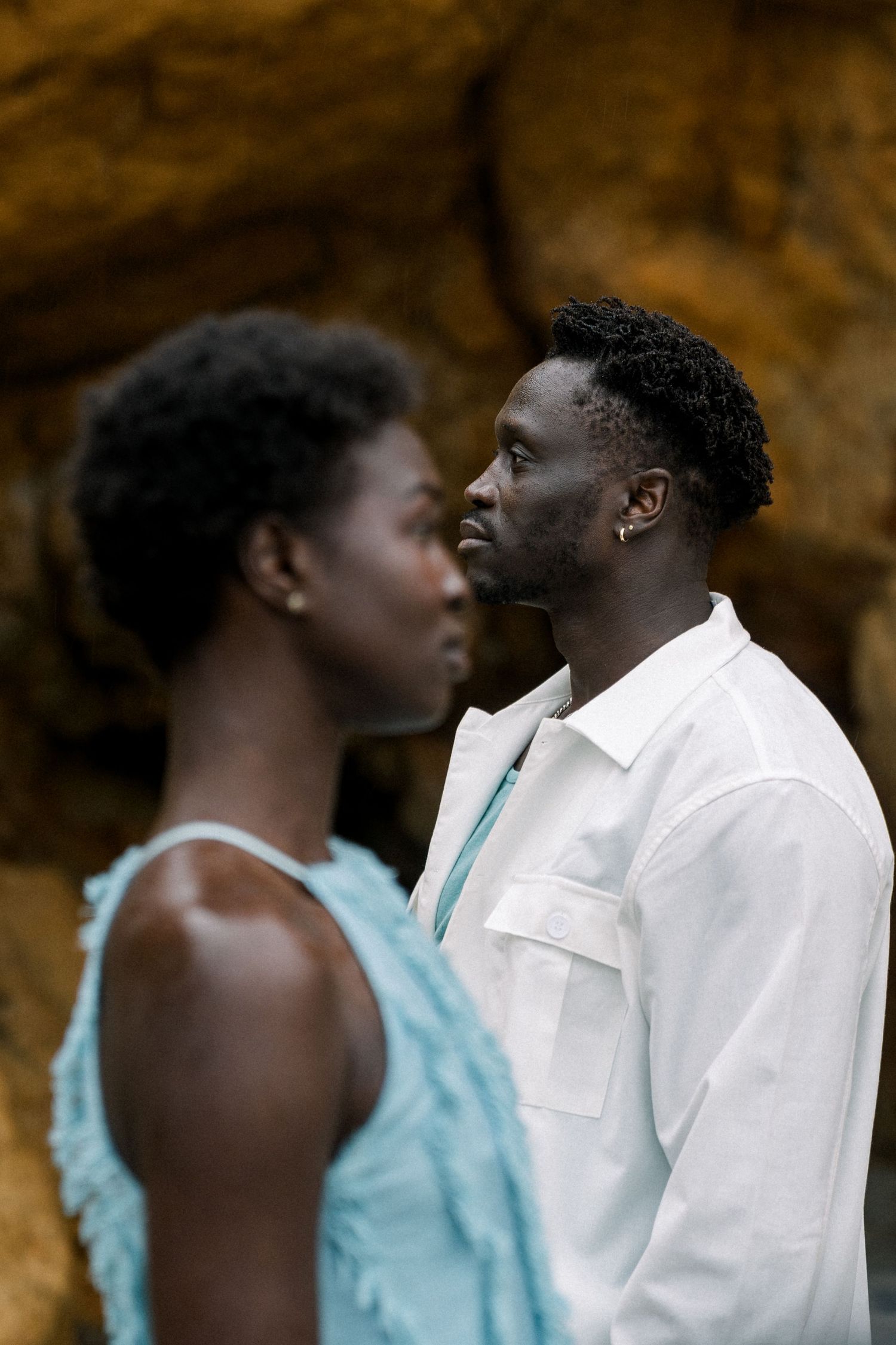 Artistic portrait of a couple in contrasting white and turquoise against natural cave backdrop.