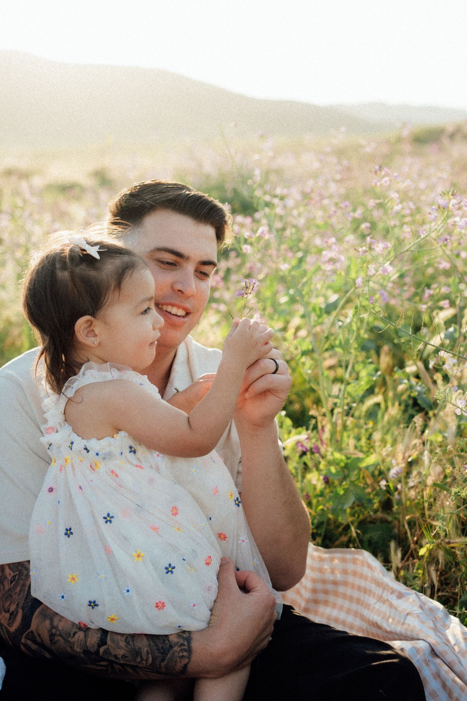 Two people enjoy a tender moment together in a blooming wildflower meadow at sunset.