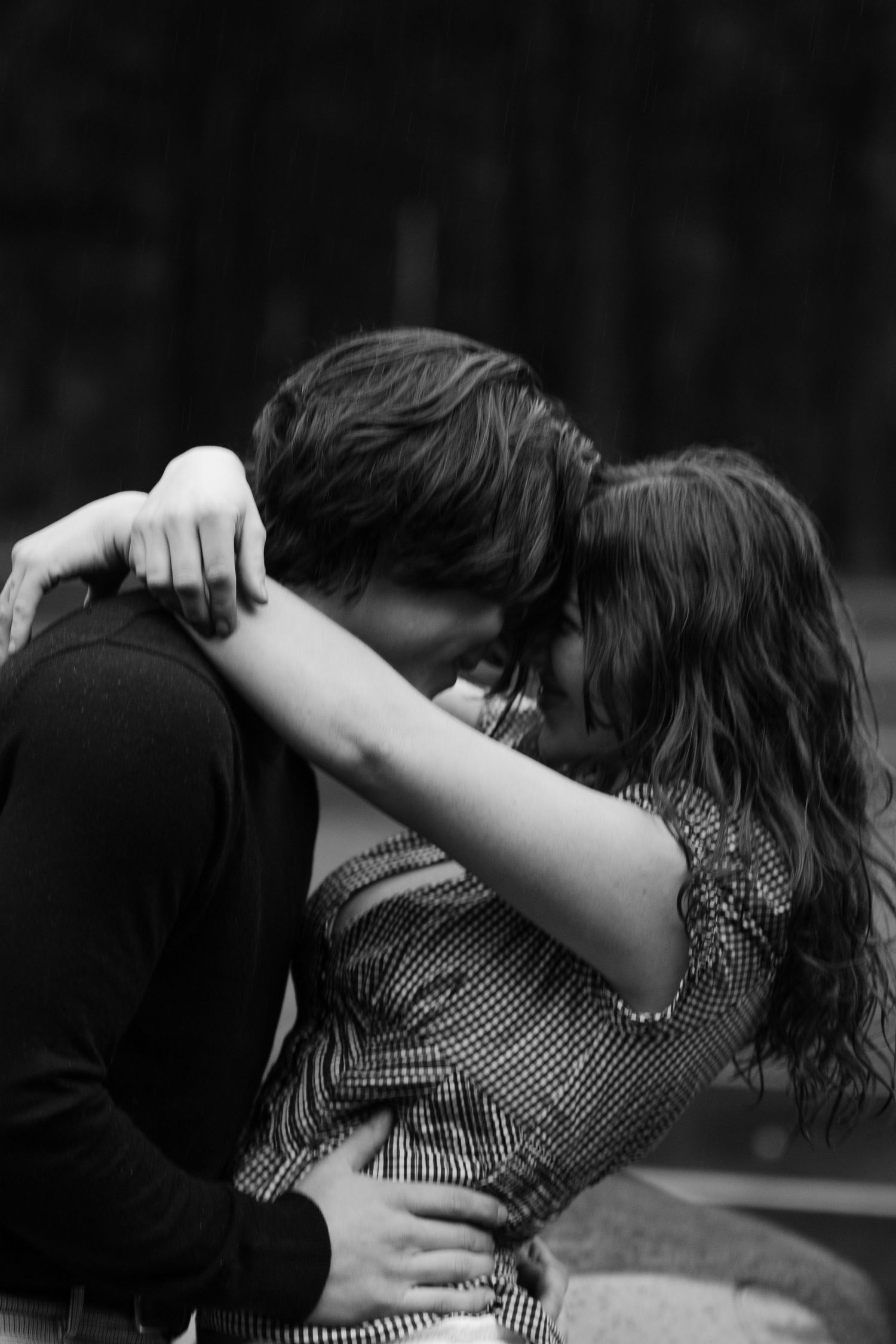Black and white photo capturing intimate embrace between couple outdoors.