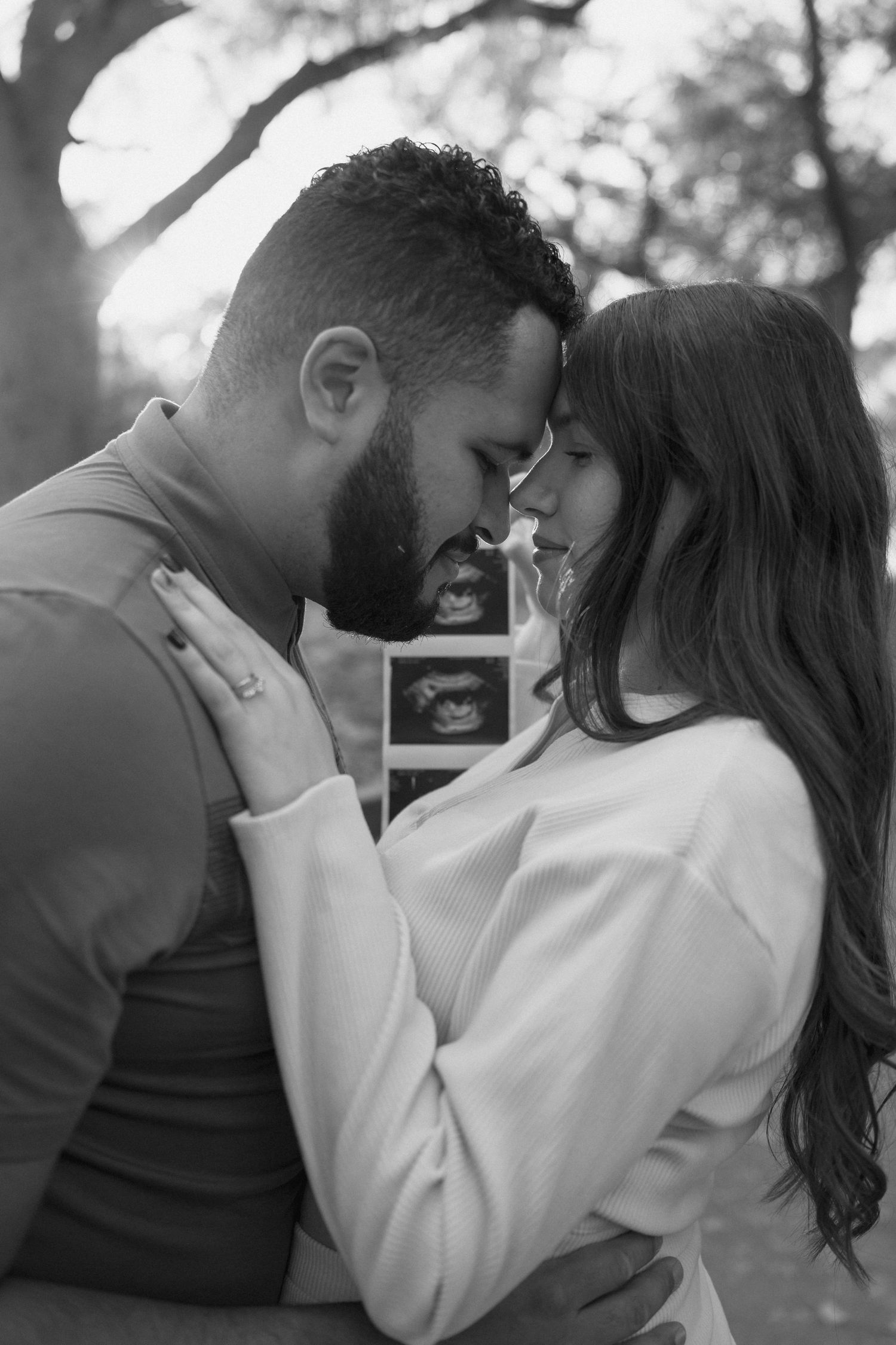 Intimate black and white portrait of couple with sonogram photo.