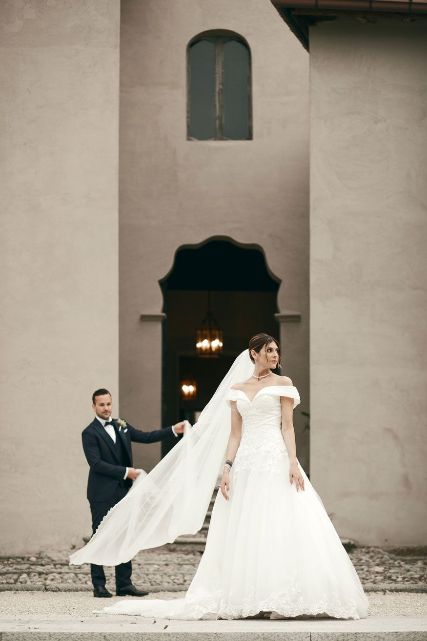 Romantica sposa con velo sollevato dallo sposo, sullo sfondo il Castello Durini in provincia di Como. Un momento elegante e senza tempo