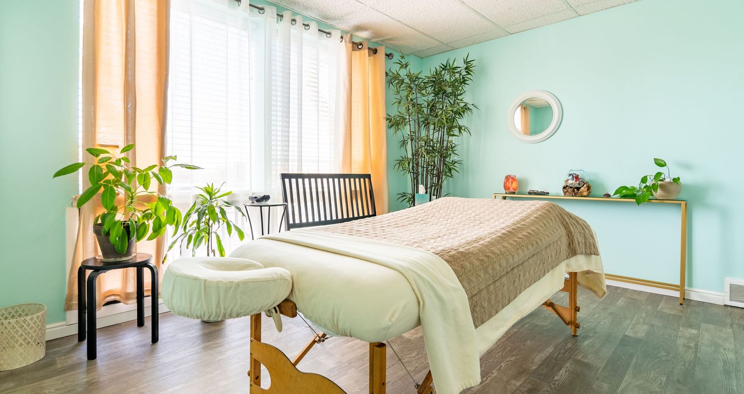 Tranquil massage room featuring teal walls, bamboo plants, and natural light.