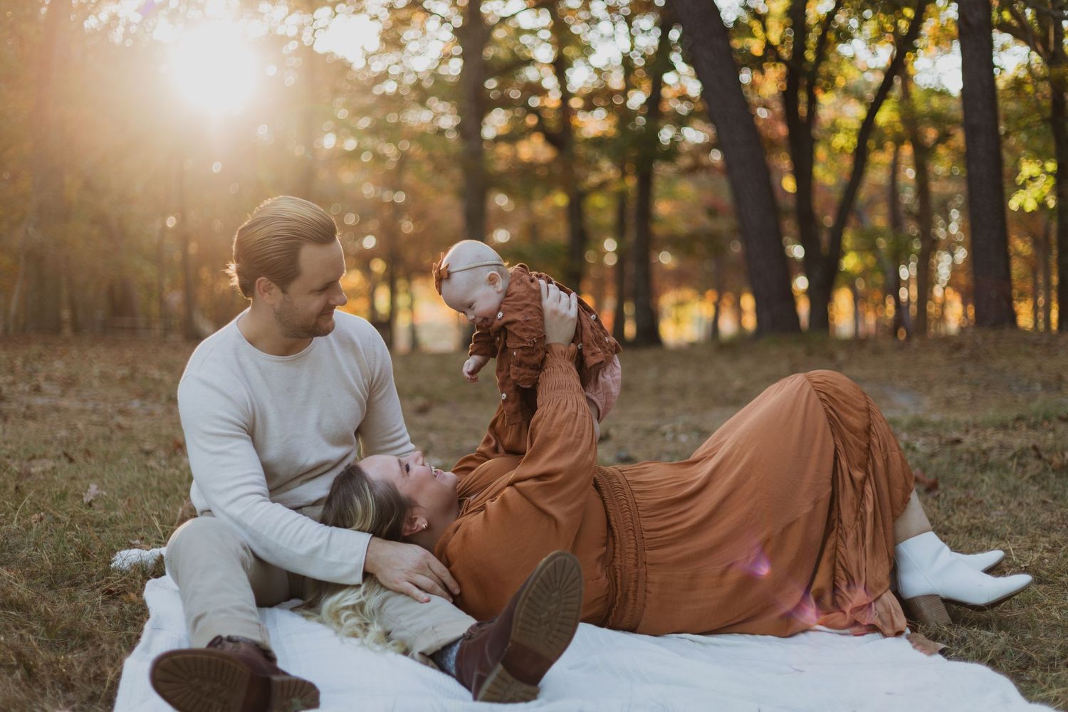 Couple enjoying a romantic sunset picnic on white blanket.