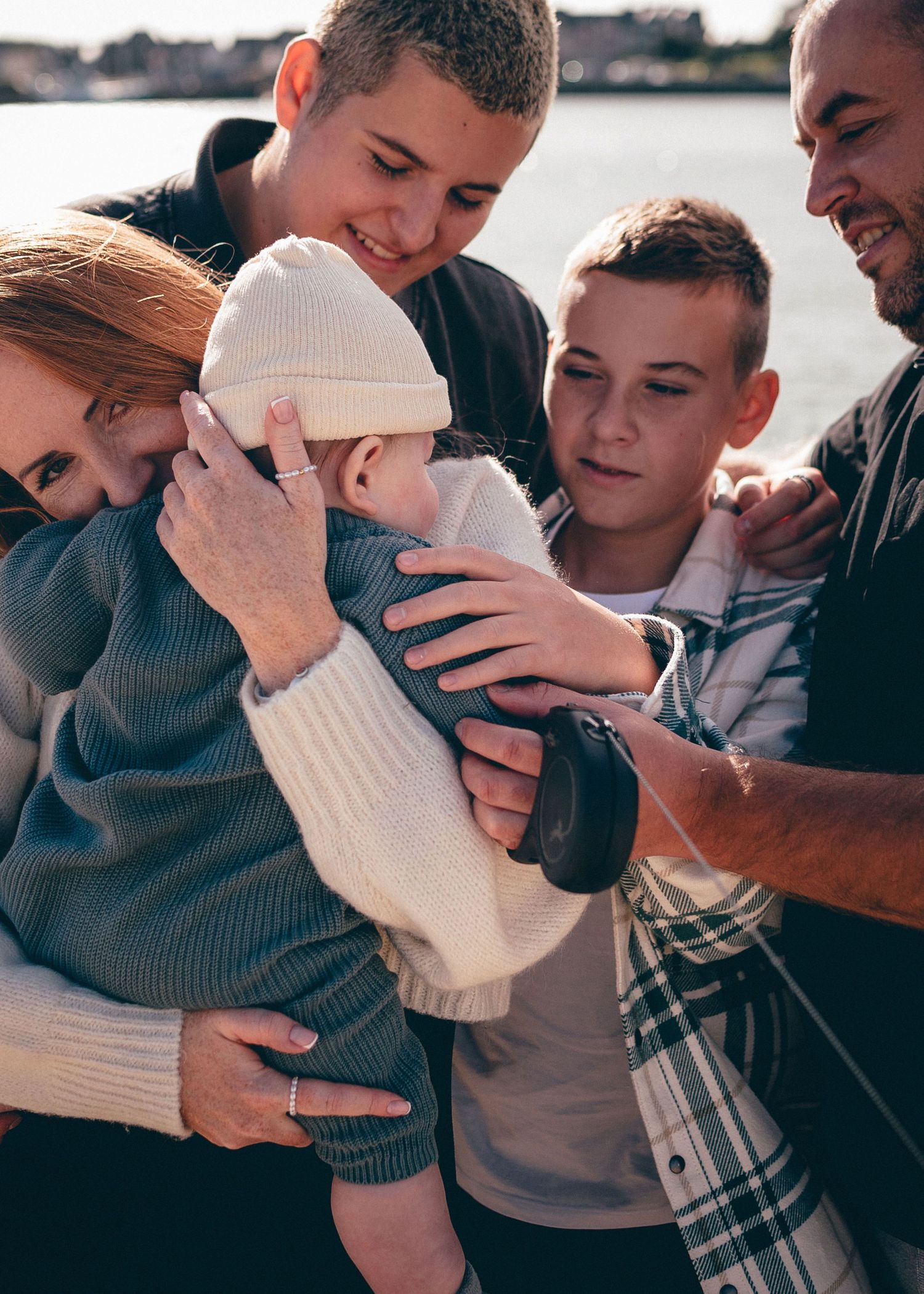 Famille réunie autour d’un bébé, échanges de regards et moment complice en extérieur à Pen Bron