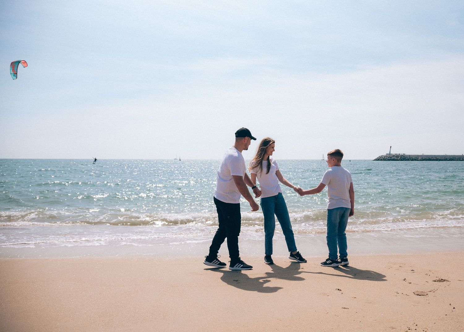 Parents et enfant se tenant la main sur la plage de La Turballe, photographie familiale en lumière naturelle