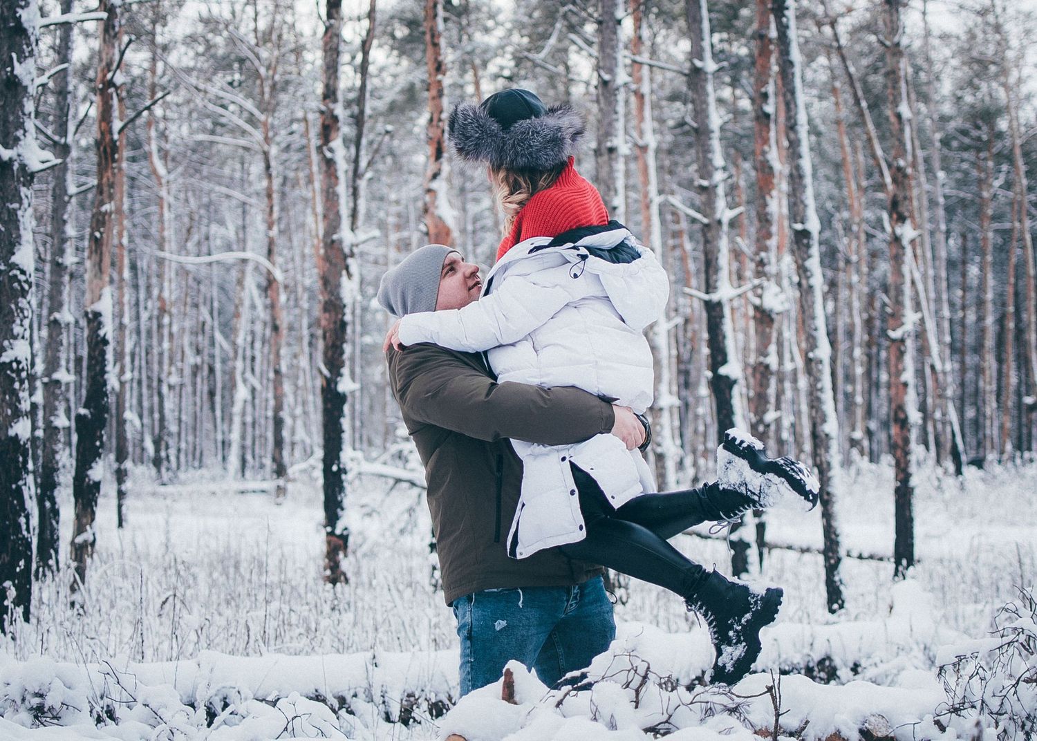 Winter forest panorama showing couple playing in deep snow.