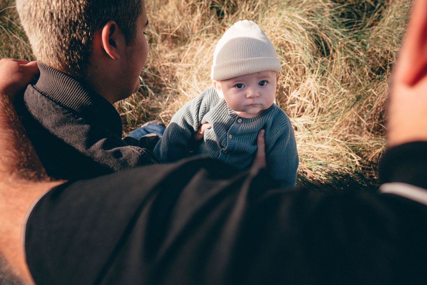 Bébé regardant ses parents en arrière-plan, scène familiale naturelle photographiée à Pen Bron