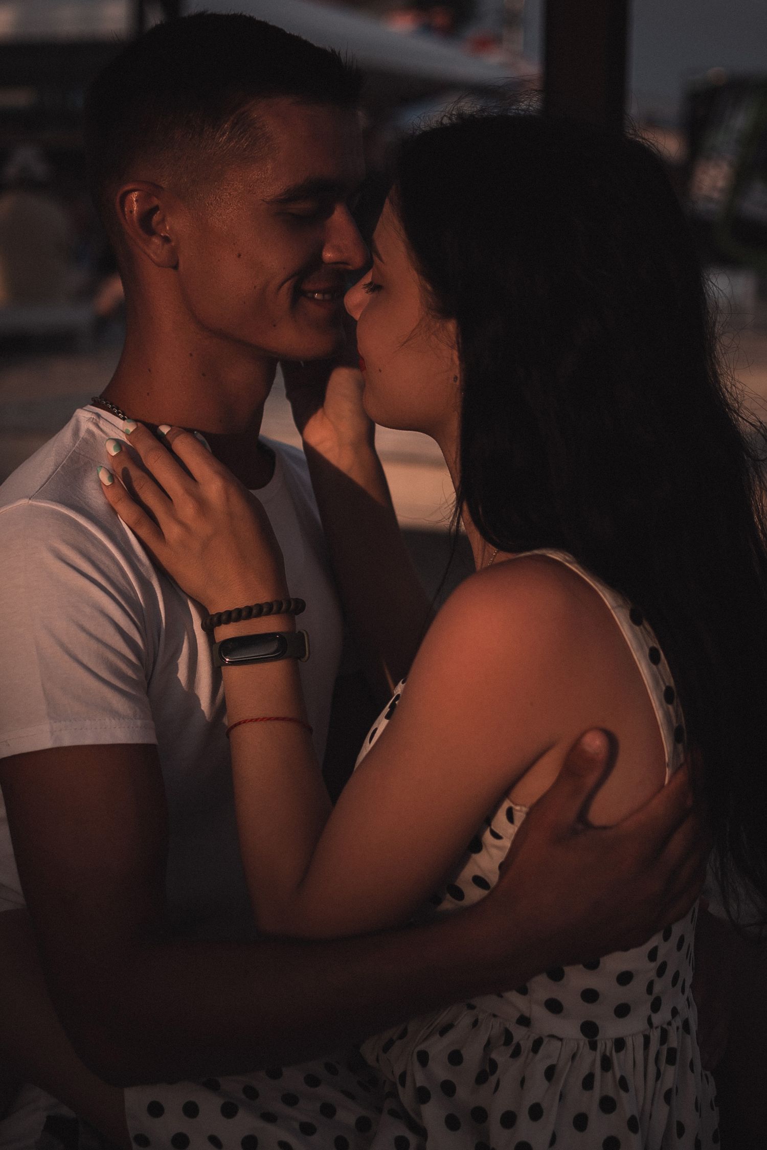 Intimate couple embracing in dim lighting with polka dot dress detail.