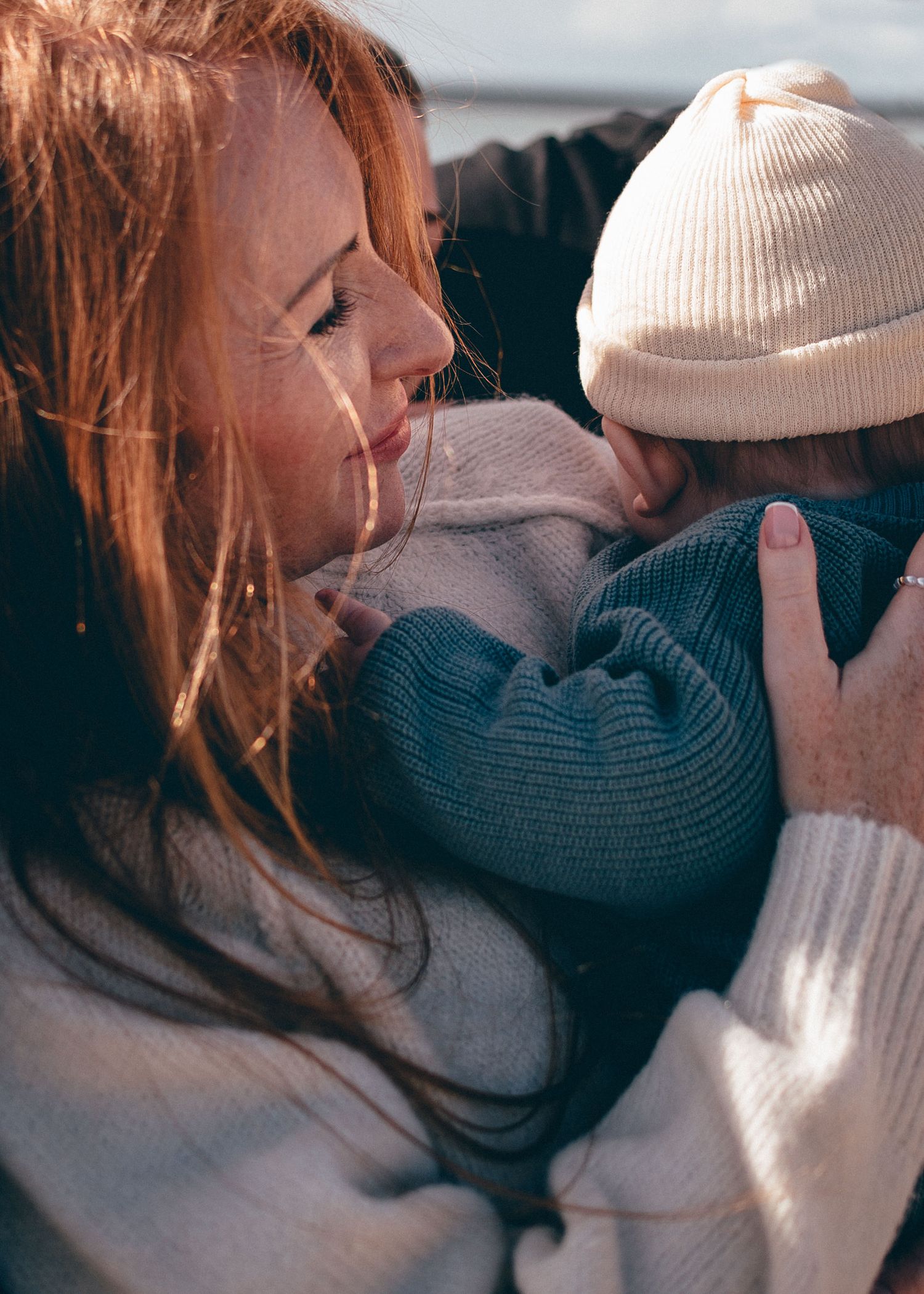 Gros plan d’une mère tenant son bébé contre elle, expression tendre et lumière naturelle à Pen Bron